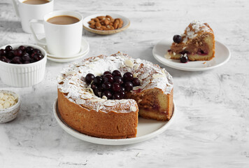 frangipane pie with frozen berries served on a table with a cup of coffee and a piece of pie