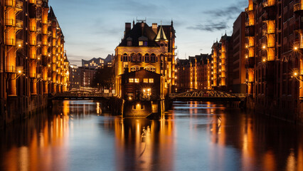 Moated castle in the Speicherstadt illuminated in the evening.