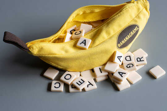 Portland, OR, USA - Dec 12, 2021: Bananagrams portable banana-shaped pouch with letter tiles isolated on a gray background. Bananagrams is a word game wherein lettered tiles are used to spell words.
