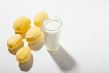 Potato milk alternative. A glass of milk and a raw potato on a white background.