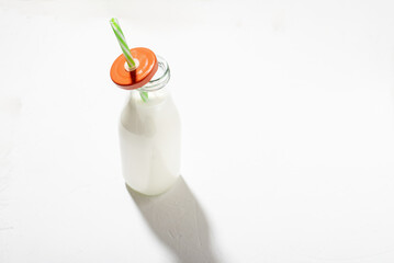 Milk in a bottle with a straw on a white background. Plant based milk or yogurt.