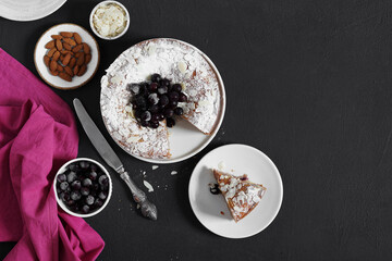 pie with frozen berries and almonds on a dark background and a piece nearly. top view, copy space