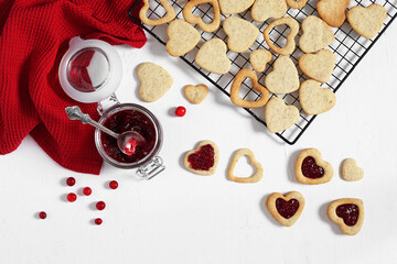 Linzer cookies filled with jam in heart foarm on a white table. top view, copy space