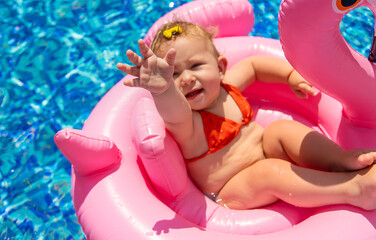 Baby swims in a circle in the pool. Selective focus.