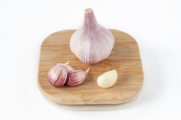 Whole garlic and cloves on a wooden stand on a light background