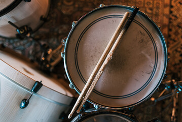 From above of worn out wooden drumsticks placed on drum on stage for rehearsal