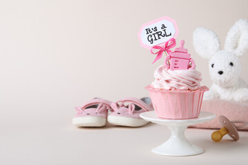 Beautifully decorated baby shower cupcake with cream and girl topper on light background. Space for text