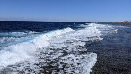 Waves on the shore of the red sea with a coral reef on a sunny, windy day