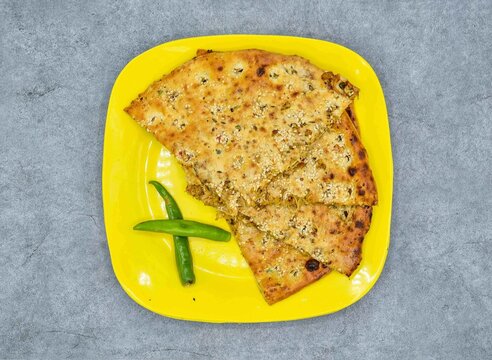 Spicy chicken qeema naan with green chili in yellow plate top view on grey background pakistani food