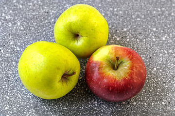 ripe juicy red and green apples grown in a personal garden on grey plastic surface close up