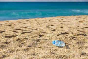 Garbage pollution of the planet. Empty plastic bottle on the beach sand. Consequences of human life