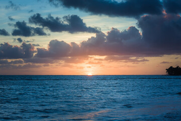 Beautiful sunrise at sea. Dawn on the Atlantic ocean. The sun is reflected in the sea. Palm trees against the background of the rising sun. Tropical sunrise. Dominican Republic