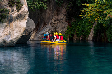 Fototapeta na wymiar tourists on an inflatable boat rafting down the blue water canyon in Goynuk, Turkey