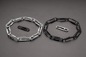 Black and white paper clips surrounded by opposite paper clips. Looped chain of paper clips