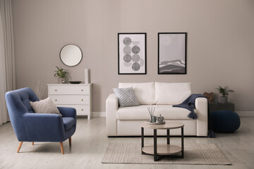 Stylish living room interior with white sofa, armchair and small coffee table