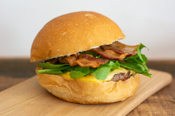 Bacon cheeseburger with bread, bacon, arugula, patty and cheese.