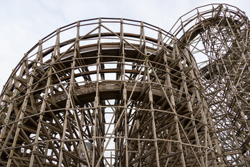 Roller coaster structure with wooden beams rising high into the sky. No visible people.