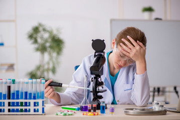 Naklejka premium Young female chemist in drugs synthesis concept