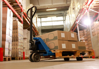 Manual forklift with cardboard boxes in warehouse. Logistics concept