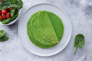 Vegan green pancakes, crepes with spinach on gray background. Plant based diet concept. flat lay...