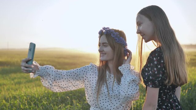 Two Ukrainian girls posing for selfies in a field.