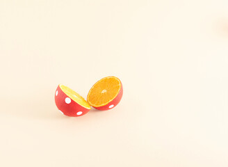 Creatively painted orange against pale, pastel orange background. Exotic summer fruit concept. Two...
