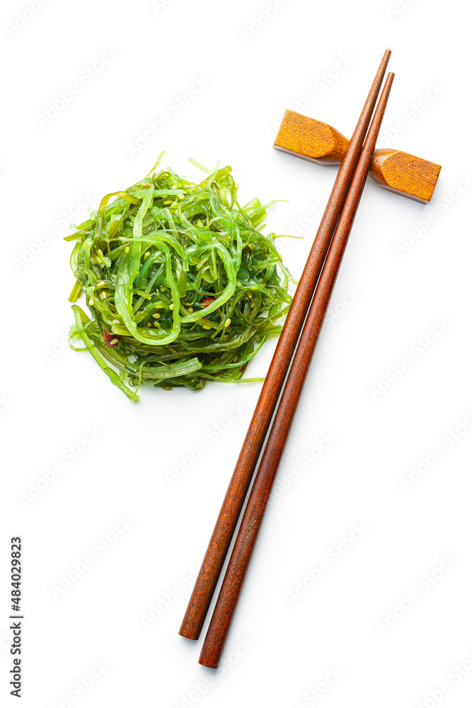 Wall mural Green wakame. Seaweed salad and chopsticks isolated on white background.