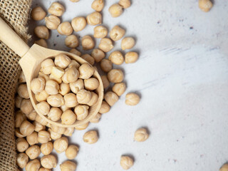 Wooden bowl and wooden spoon full of chickpeas on a light concrete background. close-up