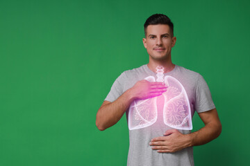 Handsome man holding hands near chest with illustration of lungs on green background. Space for text