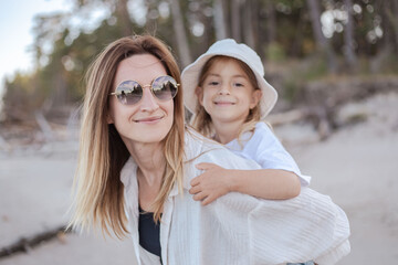 Obraz premium Mother having daughter a piggyback at the beach. Have fun together.