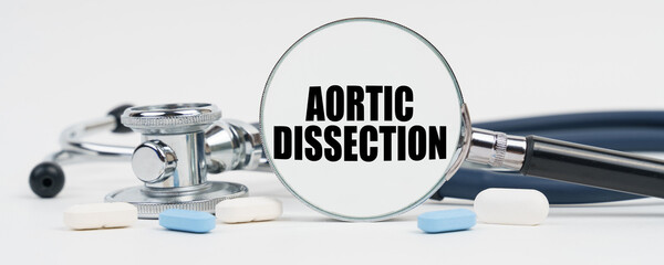 On a white surface are pills, a stethoscope and a magnifying glass inside which is written - Aortic dissection