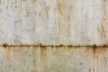 Connection of two old iron sheets on a white metal wall. There are pockets of rust. Background....