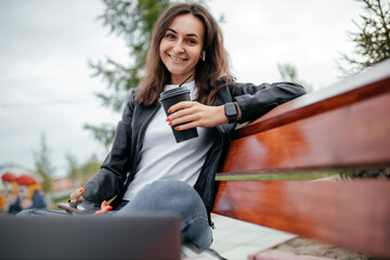 Woman girl using a computer, laptop, working remotely in the park. Distance learning online-education and work.