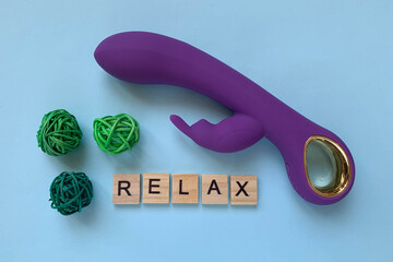 Sex toy. Purple vibrator on a blue background. Inscription RELAX. Useful for adults, sex shop