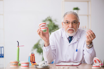 Old male doctor dentist working in the clinic