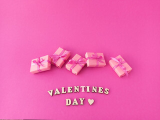 A lot of small boxes of gifts tied with a ribbon on a pink background. The concept of congratulating women on the holiday. Valentine's Day greeting card. 