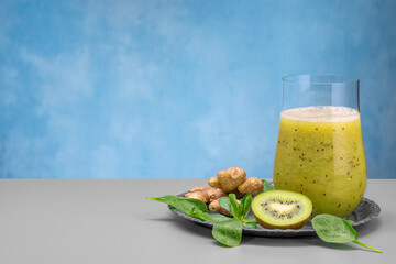 Glass of green spinach, orange, ginger and kiwi healthy smoothies.