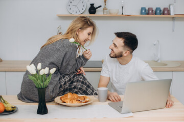 Young couple having a romantic breakfast at home in the kitchen