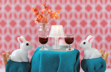 Couple of toy white rabbits on a romantic date drinking wine. Funny and ironic Saint Valentines day postcard