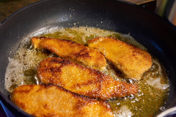 Delicious crumbed crispy golden cutlets frying in a pan