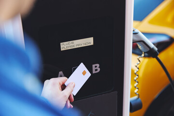 Man Charging Electric Vehicle Paying For Energy With Credit Card At Charging Station