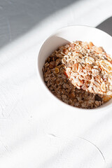 Delicious raw breakfast muesli in white thought on white table in the early morning at sunrise