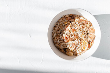 Delicious raw breakfast muesli in white thought on white table in the early morning at sunrise