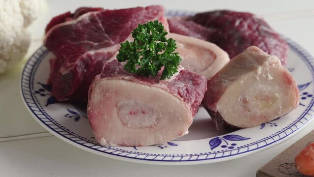 Putting a fresh parsley twig on marrow bones - ingredient to prepare beef broth or soup