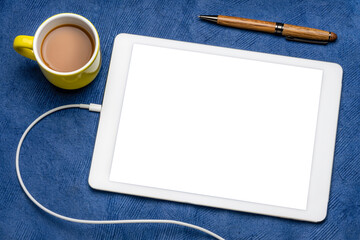 mockup of digital tablet with a blank isolated screen (clipping path included), flat lay with a cup of coffee on blue textured paper