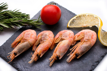 Raw shrimp on a plate with lemon and rosemary. Beautiful serving of a restaurant dish with shrimp