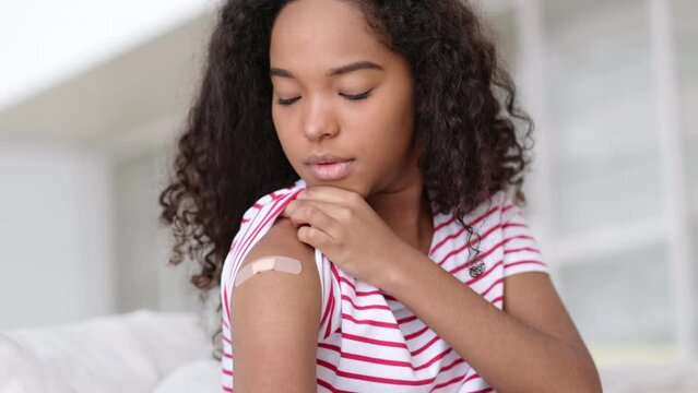 vaccinated African American woman showing arm with medical plaster patch Plaster On Shoulder, black female after getting vaccine dose against covid. Healthcare immunization, coronavirus vaccination