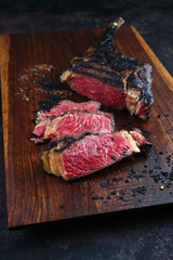 Modern style barbecue dry aged Chianina tomahawk steak sliced and served as close-up on a wooden...