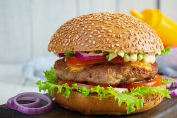 Homemade classic hamburger with beef cutlet, cheese, lettuce and tomato on wooden background