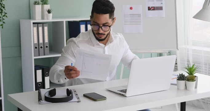 Businessman working on laptop and analyzing document at office